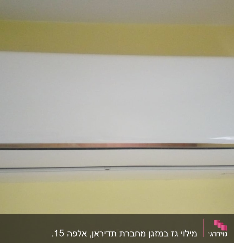 מזגן קיר לבן מותקן על קיר צהוב